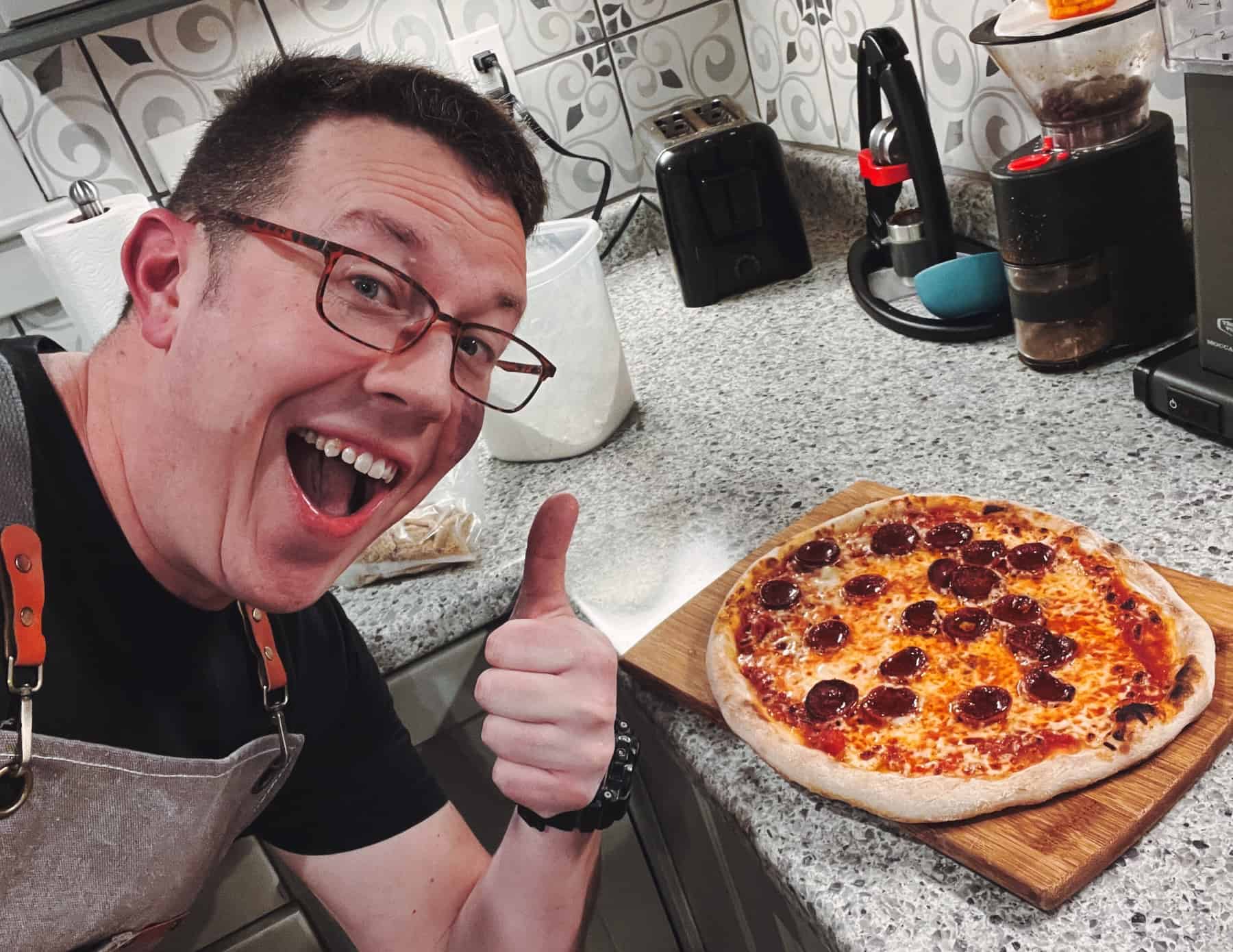 Pete giving a thumbs up next to a fresh homemade pepperoni pizza